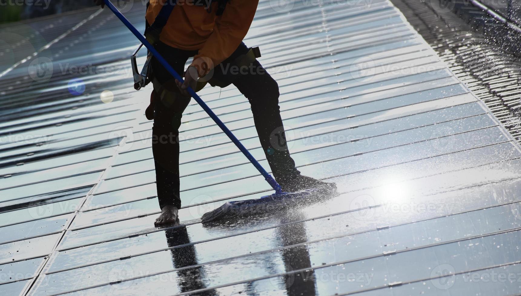 Photovoltaic technicians were cleaning and washing the surface of the solar panels which had dust and birds' pooping photo