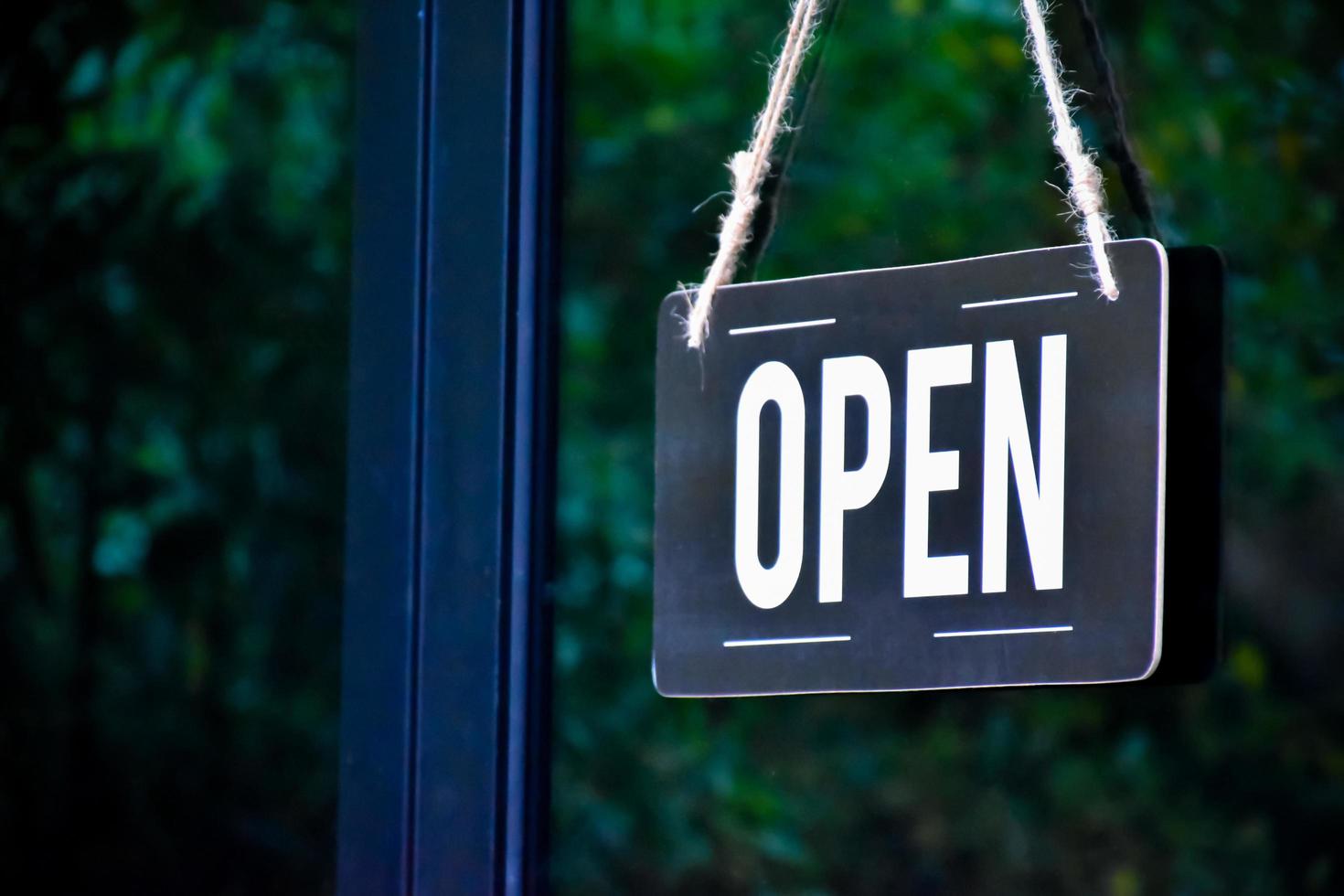 una etiqueta de tienda abierta que cuelga en la puerta de cristal de la tienda, concepto para informar a las personas en situaciones de crisis de covid19 en todo el mundo. foto