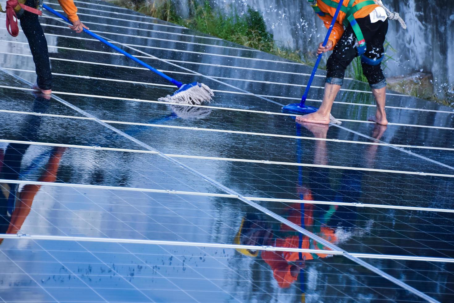 Photovoltaic technicians were cleaning and washing the surface of the solar panels which had dust and birds' pooping photo