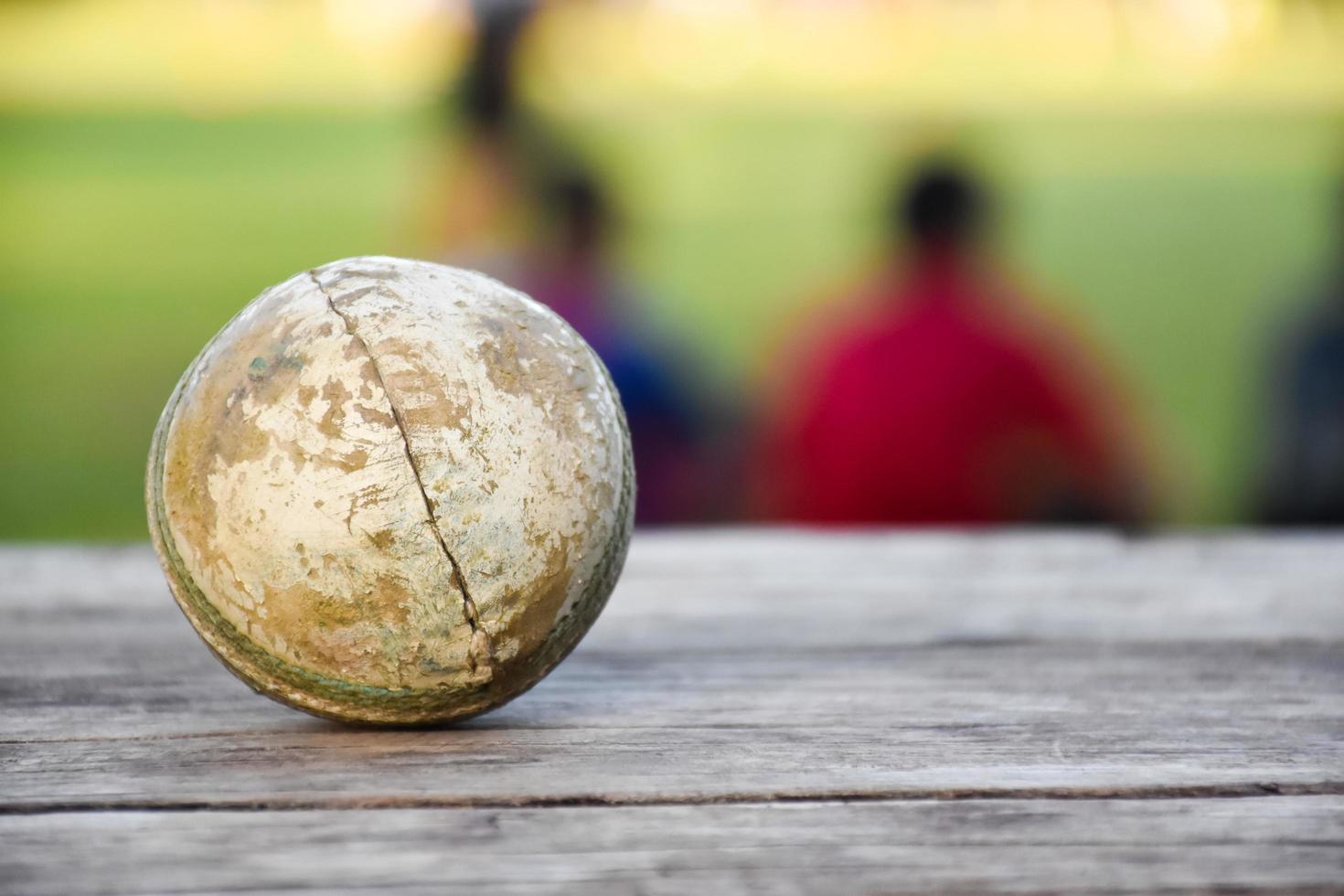 Old training cricket sport equipments on dark floor, leather ball, wickets, helmet and wooden bat, soft and selective focus, traditional cricket sport lovers around the world concept. photo