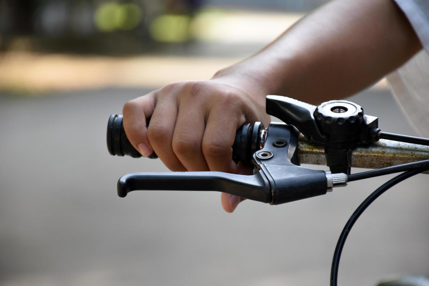 Closeup view of handlebar of bicycle which has hand of kid holding it. photo