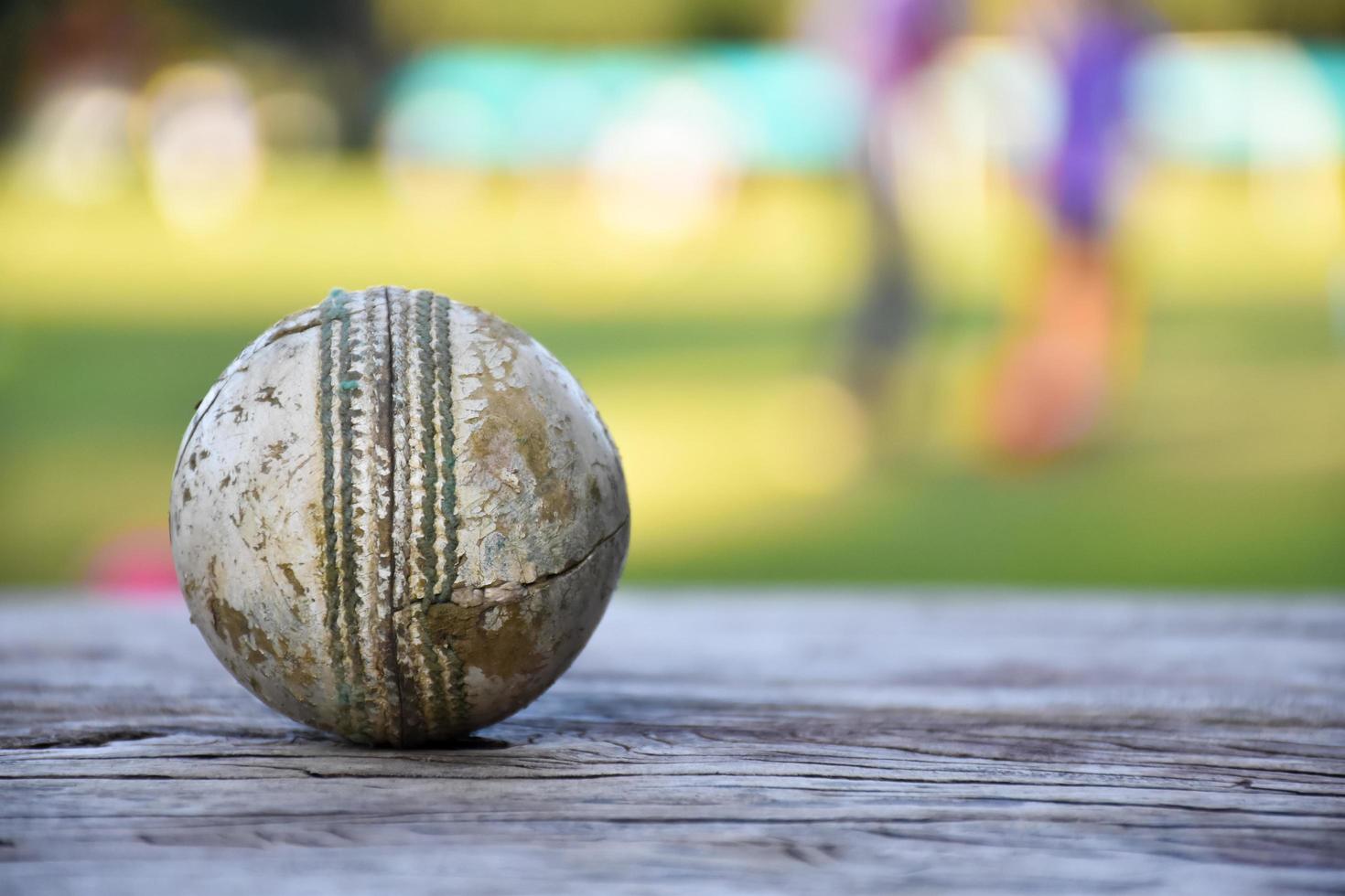 Old training cricket sport equipments on dark floor, leather ball, wickets, helmet and wooden bat, soft and selective focus, traditional cricket sport lovers around the world concept. photo