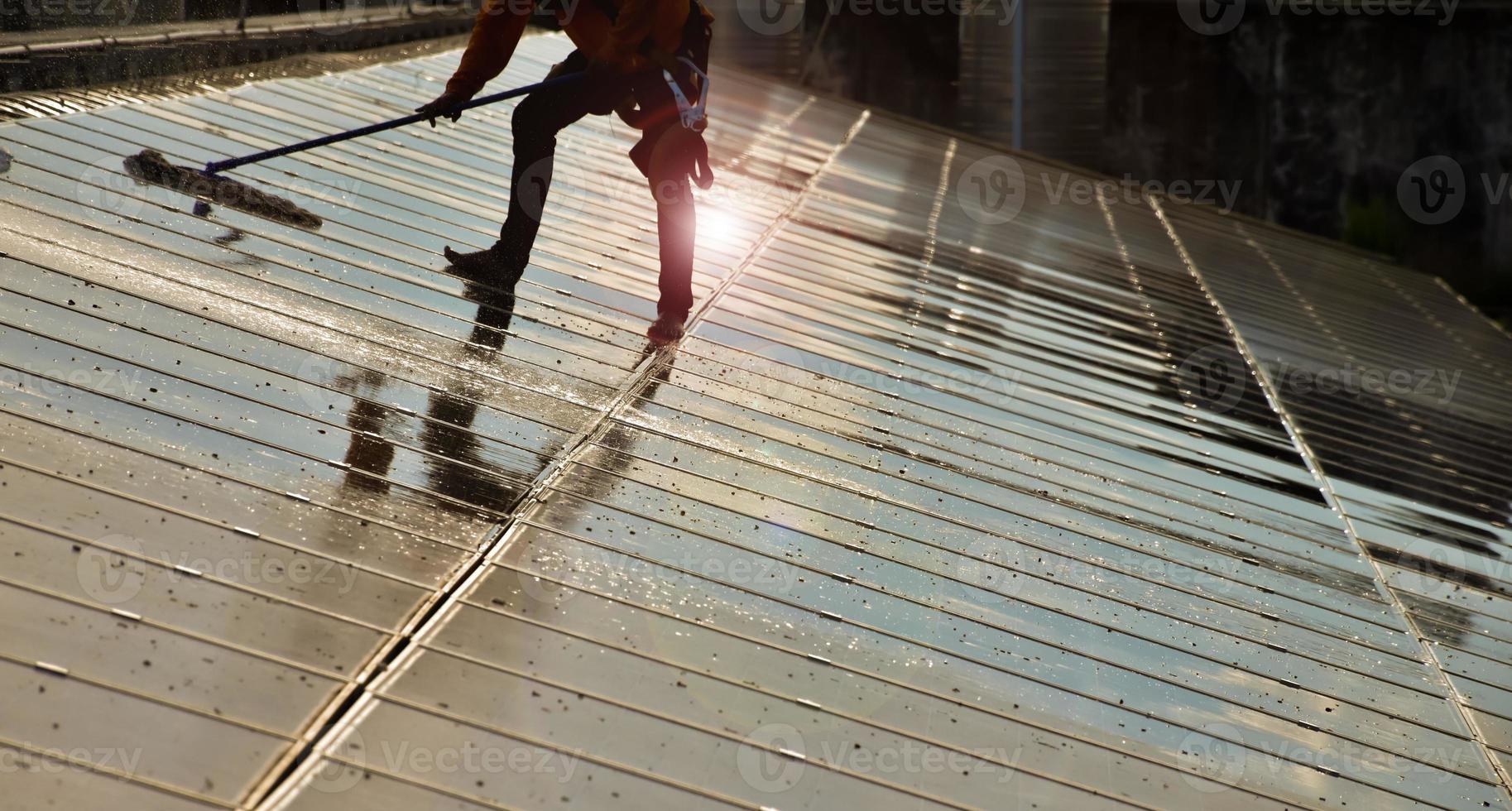 Photovoltaic technicians were cleaning and washing the surface of the solar panels which had dust and birds' pooping photo