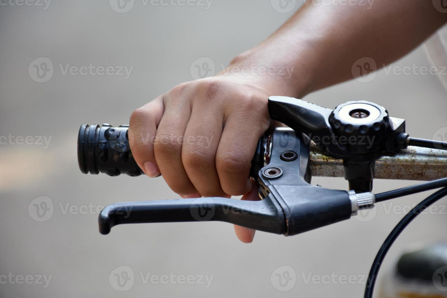 Closeup view of handlebar of bicycle which has hand of kid holding it. photo