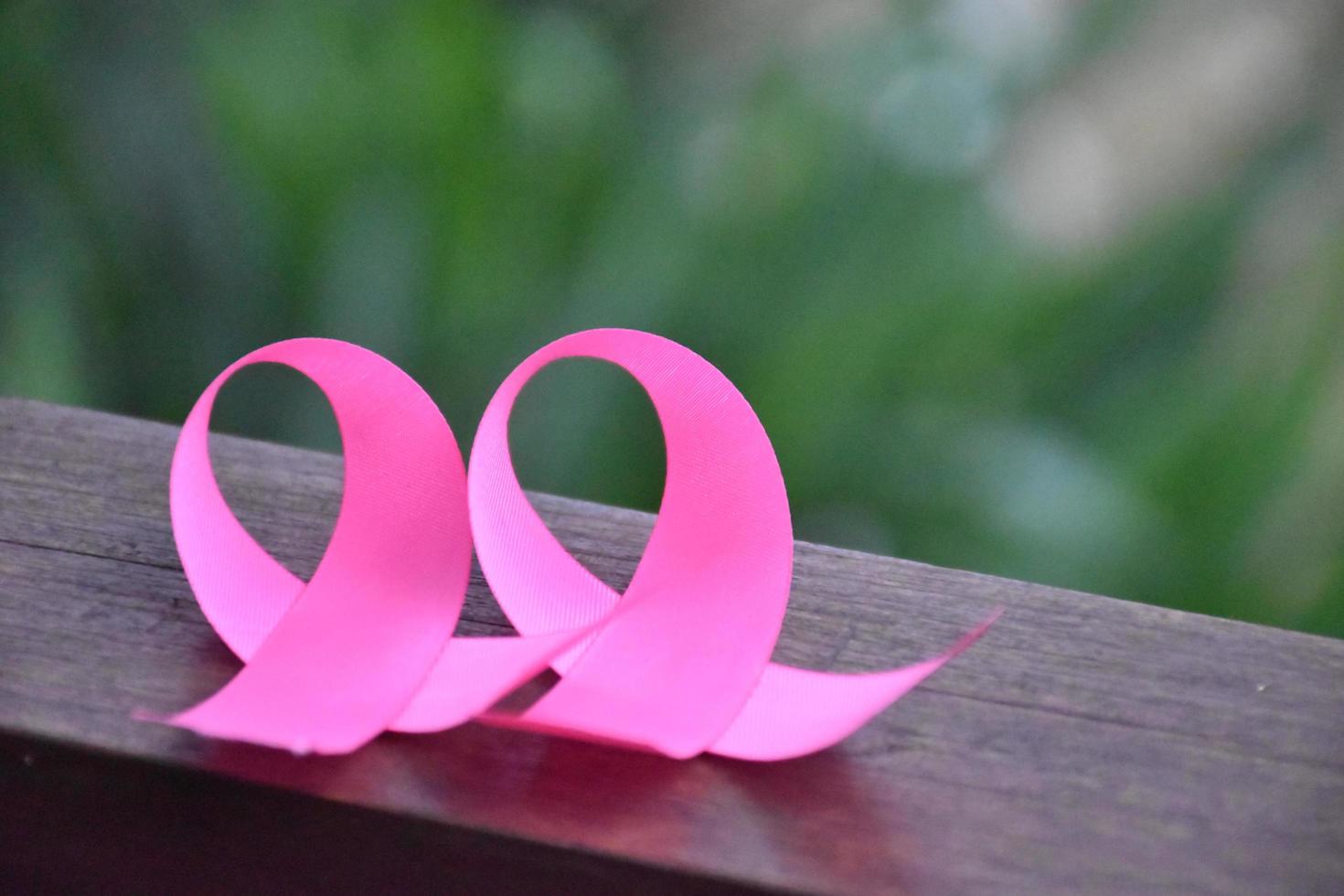 Pink ribbon on wooden table, concept for fighting against breast cancer in woman around the world. Selective focus and copy space. photo