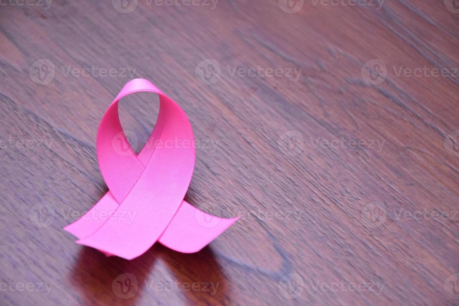 cinta rosa en la mesa de madera, concepto para luchar contra el cáncer de mama en mujeres de todo el mundo. enfoque selectivo y espacio de copia. foto