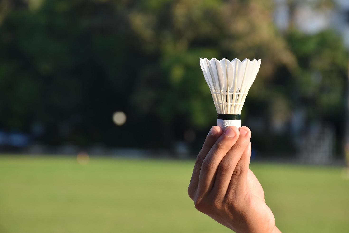 white badminton shuttlecock holding in hand. photo