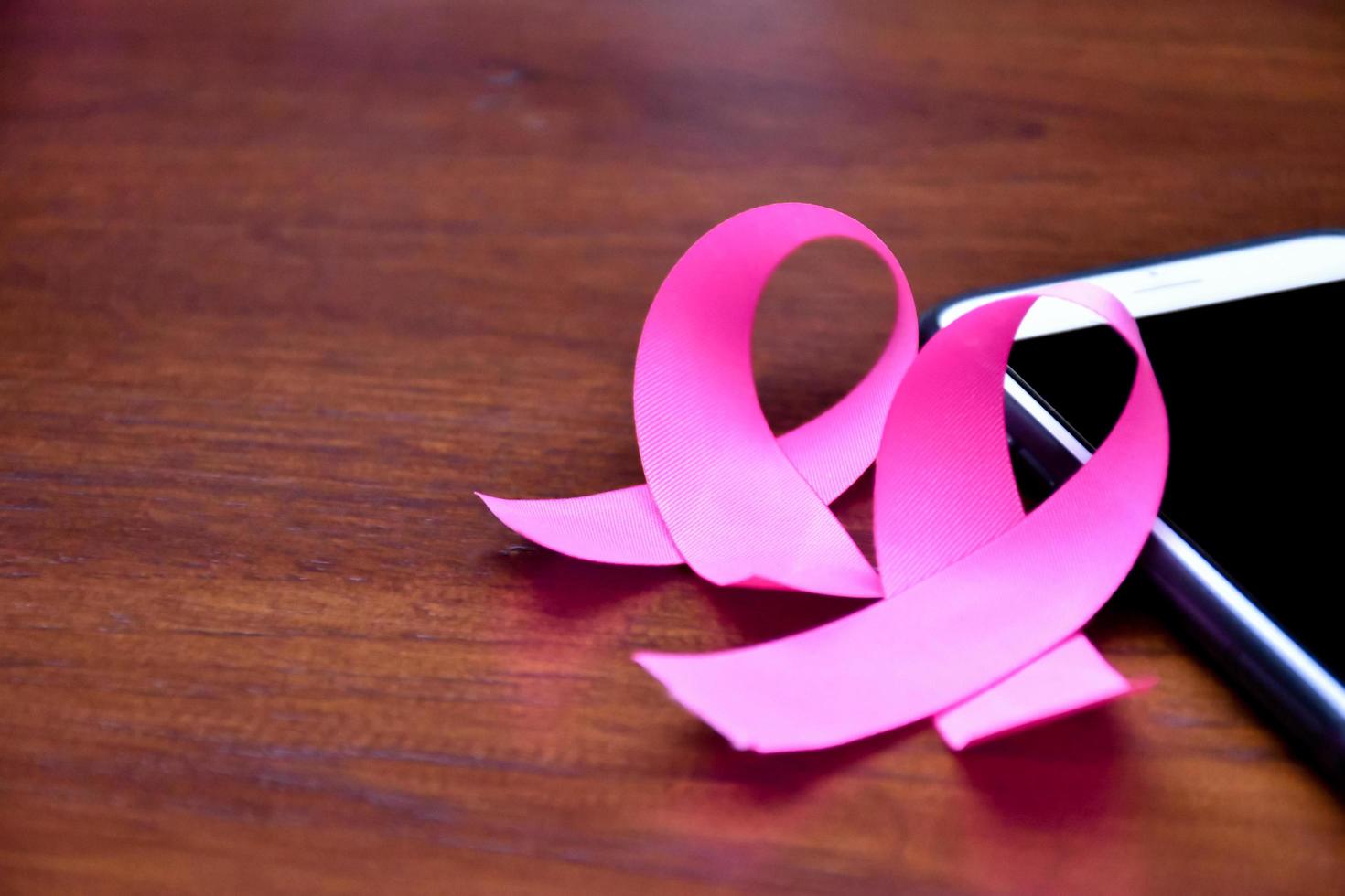 Pink ribbon on table with mobile phone. Concept for protesting and supporting the breast cancer against in woman. photo