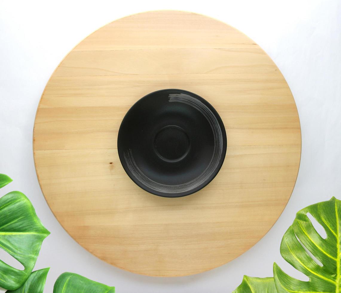 dish is placed on a round wooden table with monstera palm leaves for decoration photo