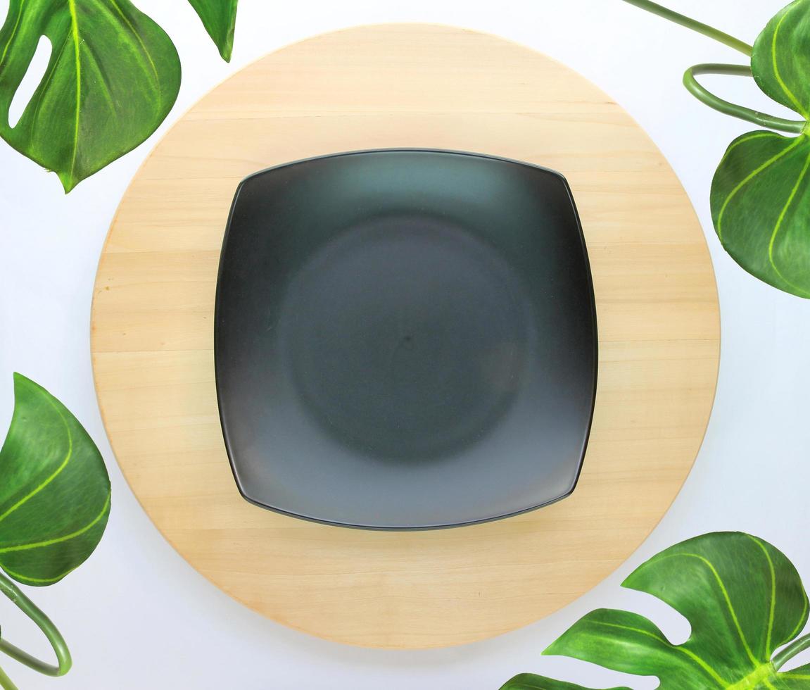 dish is placed on a round wooden table with monstera palm leaves for decoration photo