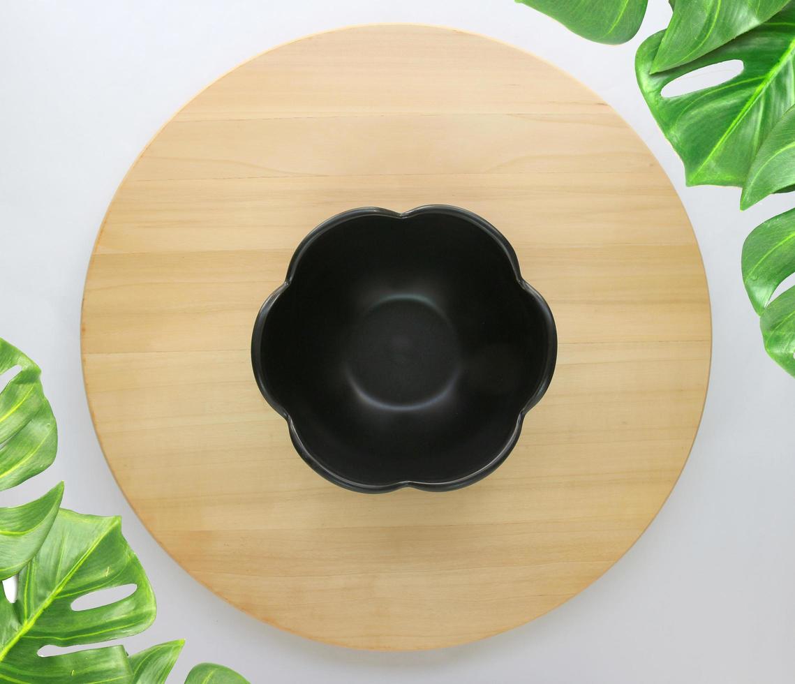 dish is placed on a round wooden table with monstera palm leaves for decoration photo