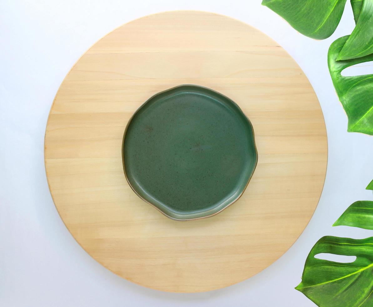 dish is placed on a round wooden table with monstera palm leaves for decoration photo