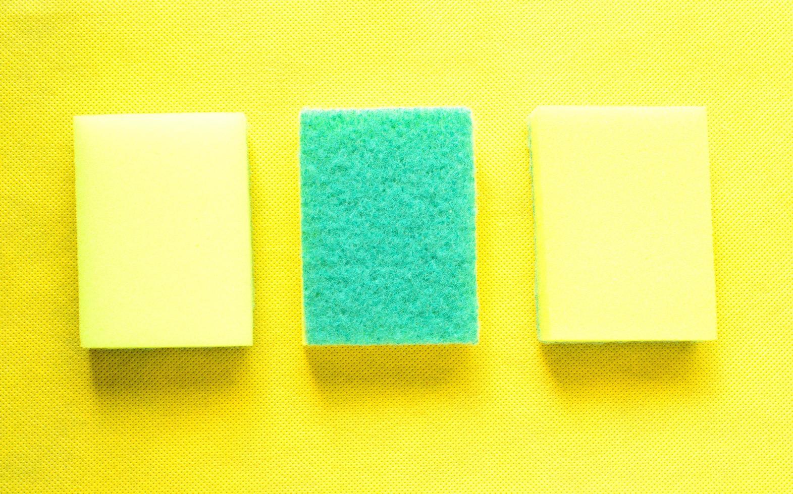 Three yellow sponges on yellow background. photo