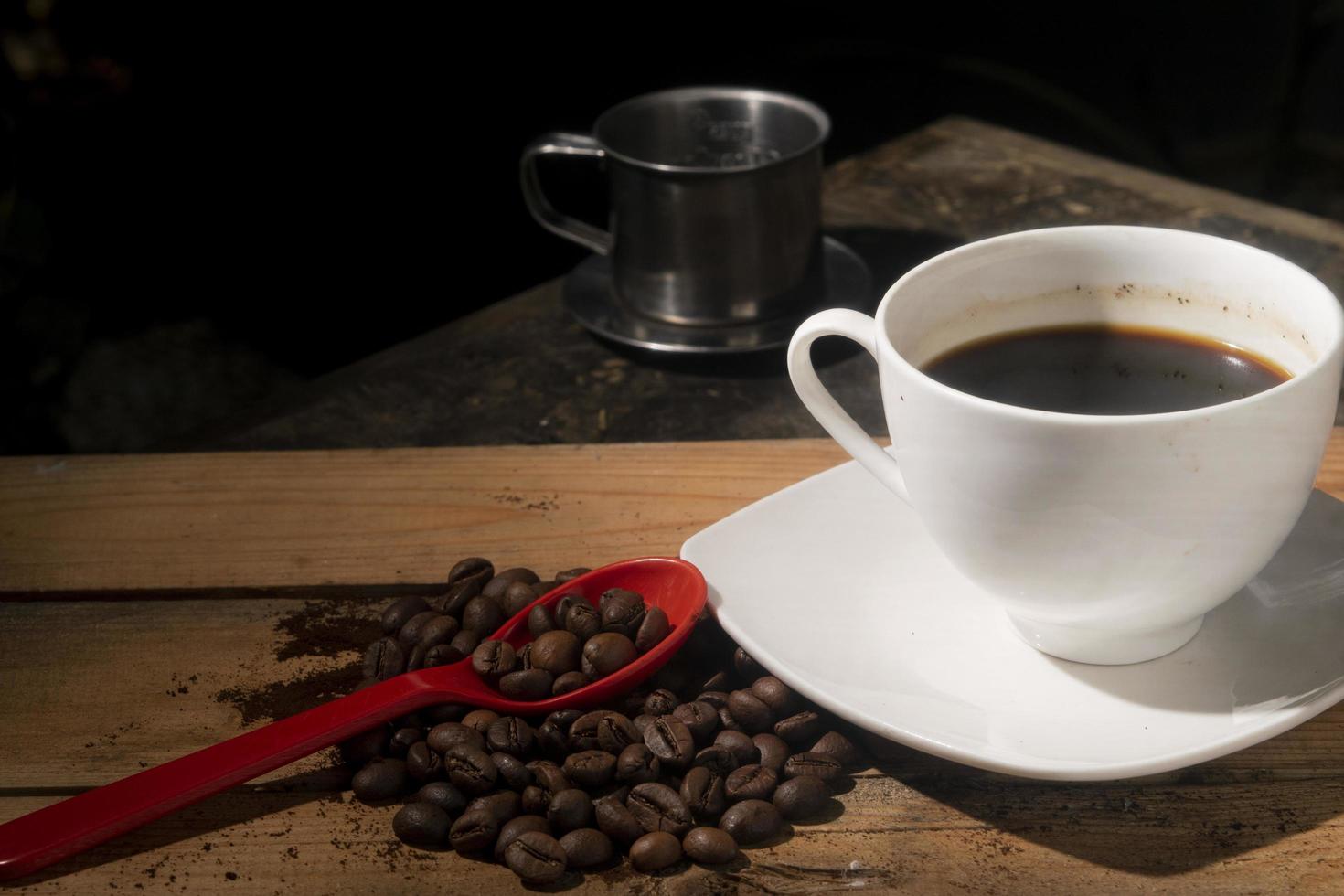 coffee beans on red spoon with black coffee on cup photo