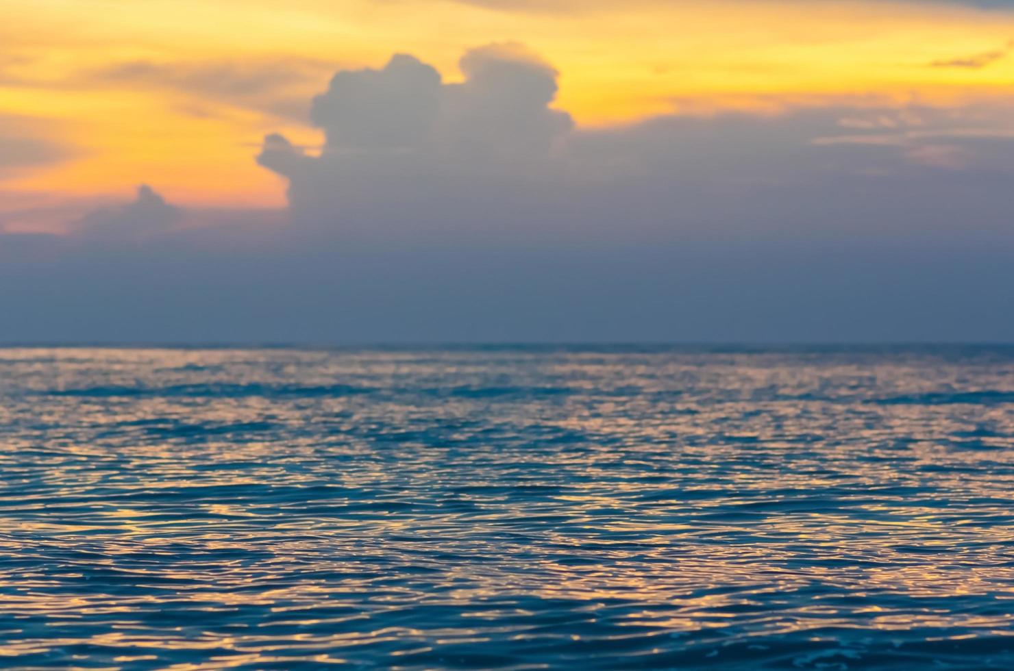 Partial focus of the sea that have sun light reflection with yellow sky and cloud when sunset. photo