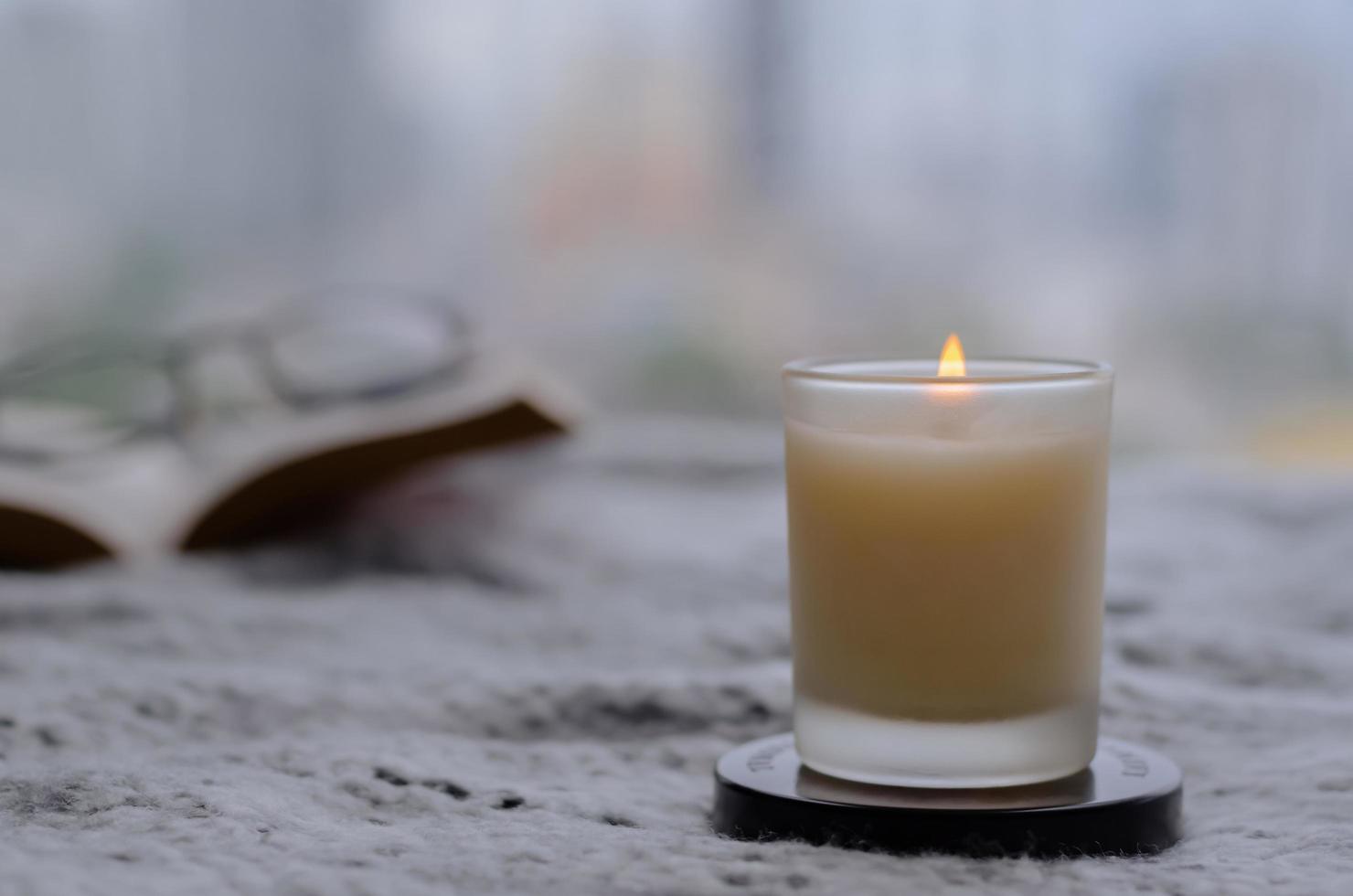 Flame burning at blurred aroma candle for relaxing when reading book at home in winter season. photo