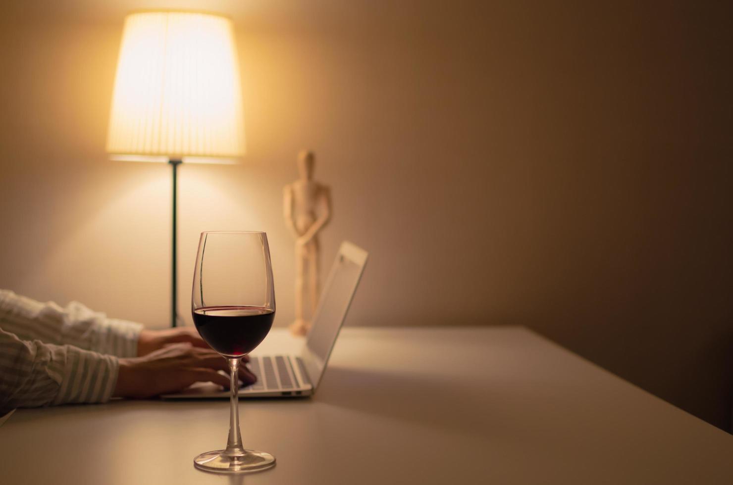 A glass of red wine puts on table to drink and relax when working at home. photo