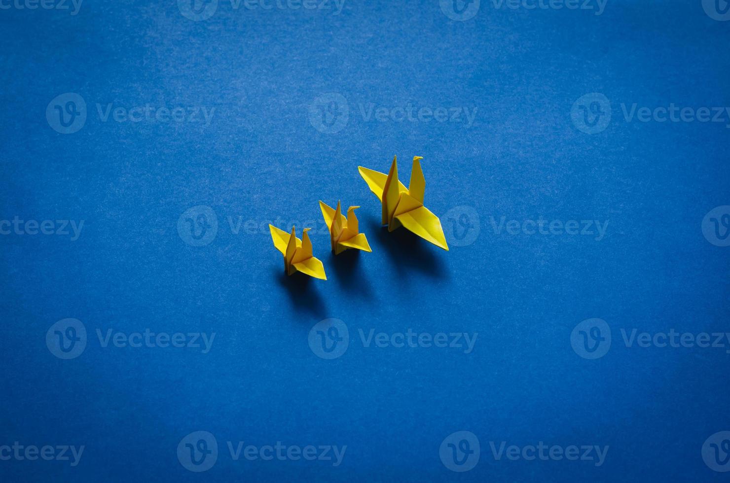Yellow paper mother and baby birds on blue background. photo
