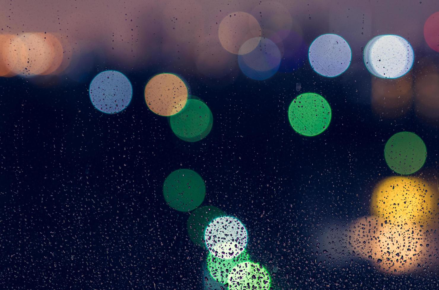 Rain drop on glass window in monsoon season with colorful bokeh lights for abstract and background concept. photo