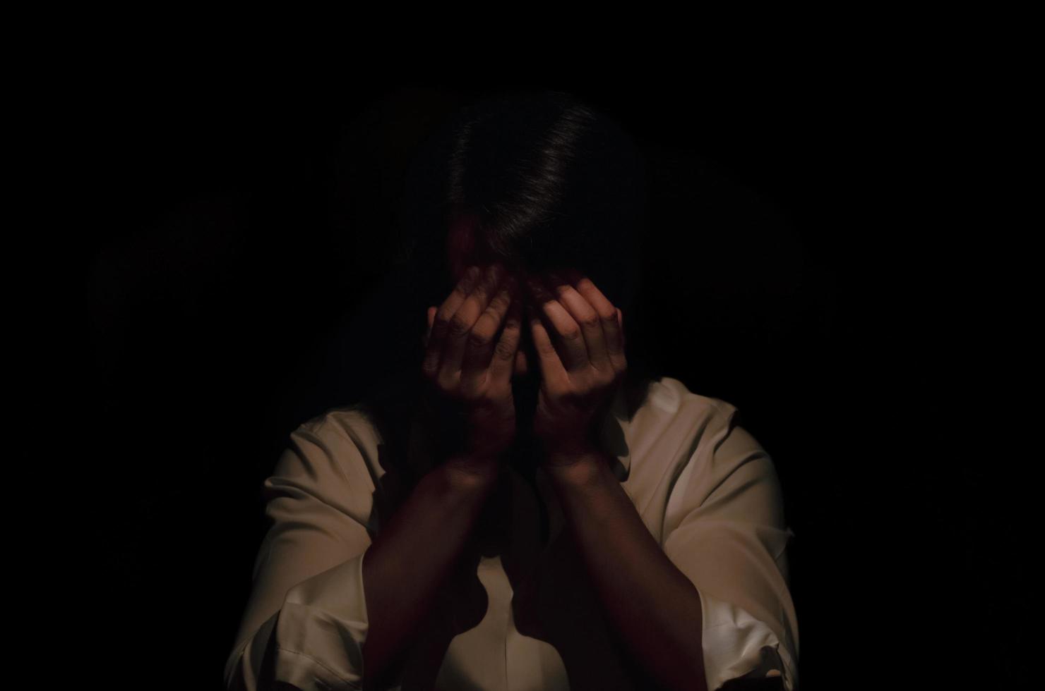Asian miserable depressed man sitting and sobbing alone in dark background. Depression and mental health concept. photo