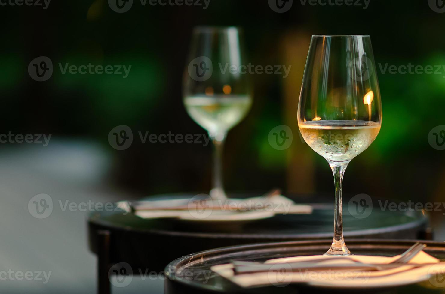 Two glasses of white wine on table with green background from garden. photo