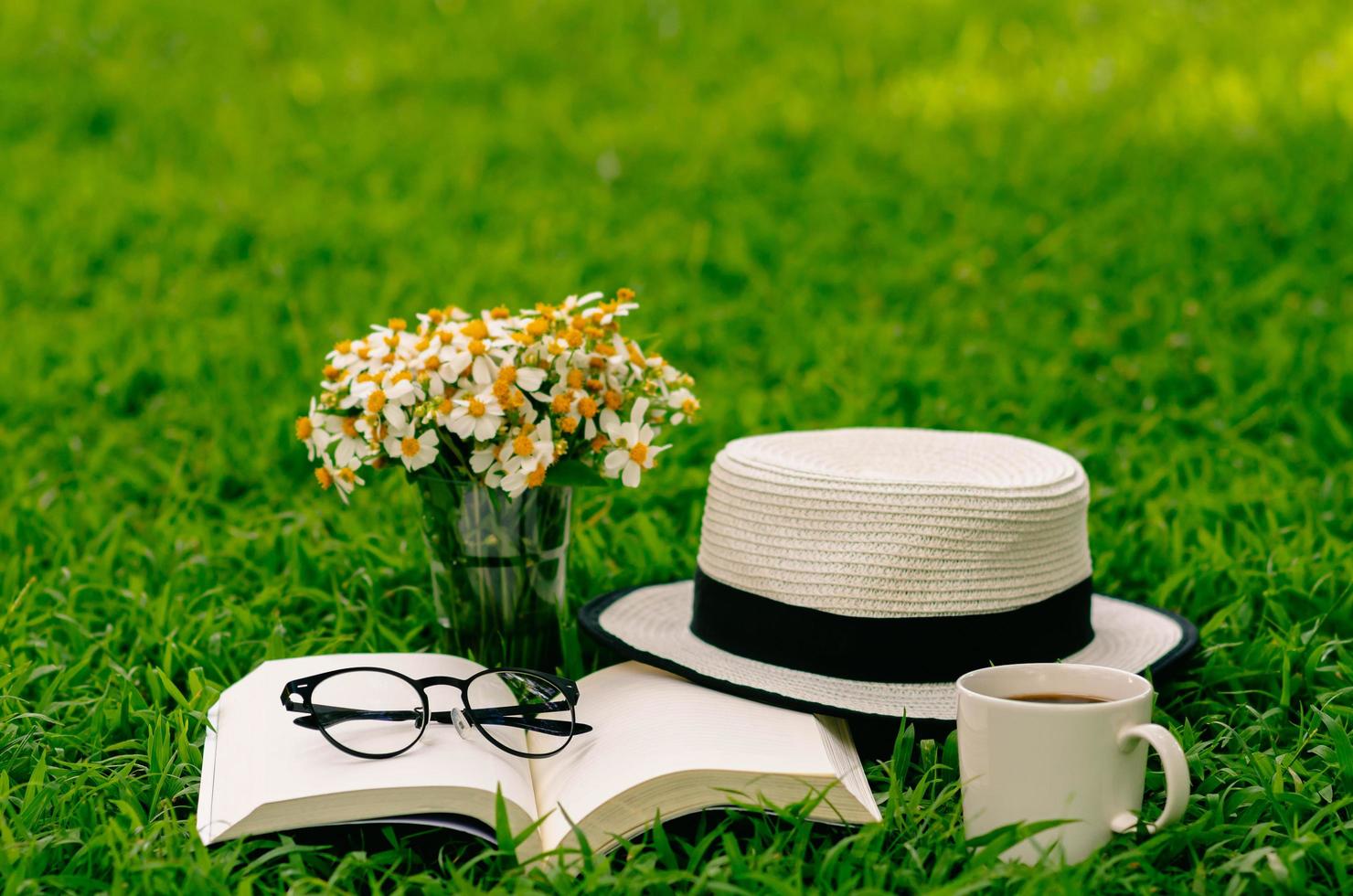 Leisure in morning at garden with coffee, book , hat and flowers on the lawn. photo