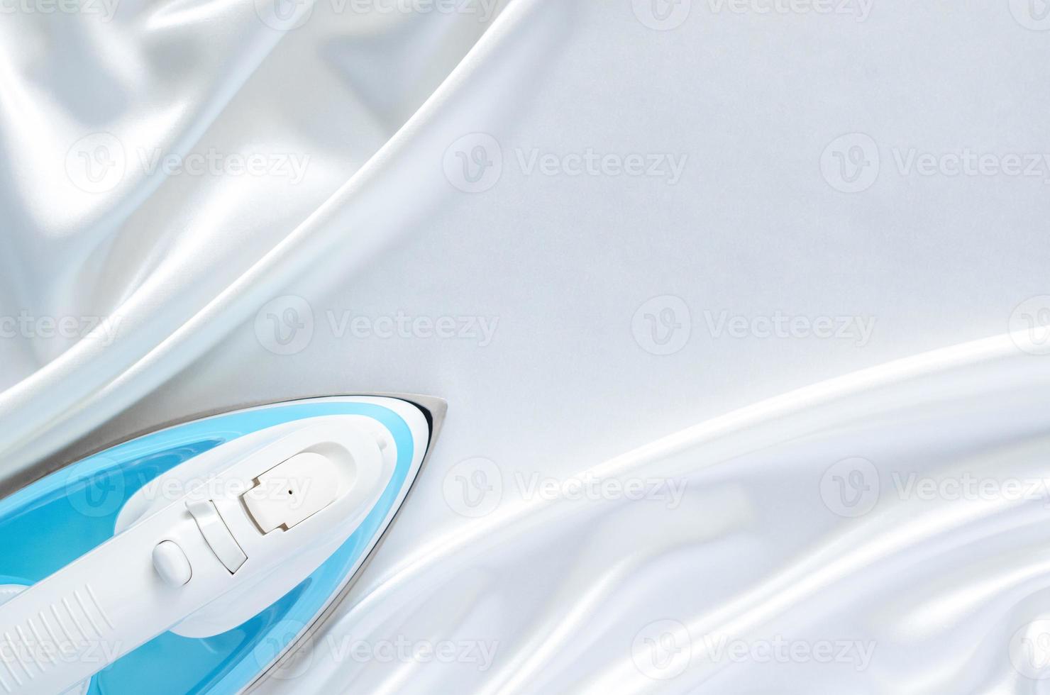 Electric iron on smooth and wavy white cloth texture with space for text. photo