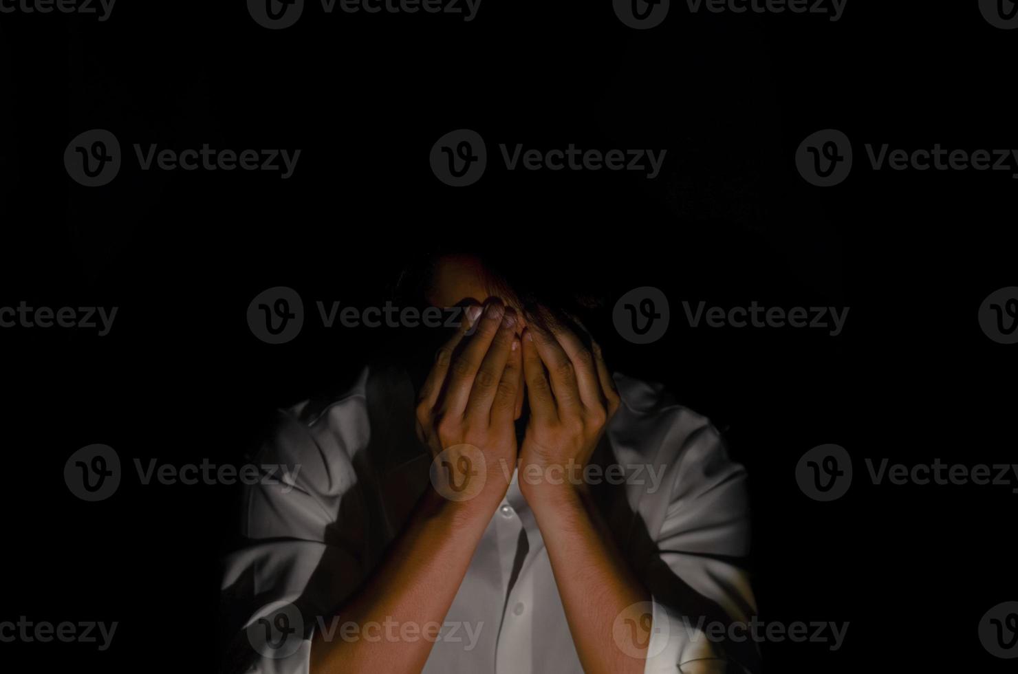Miserable depressed man sitting alone in dark background. Depression and mental health concept. photo