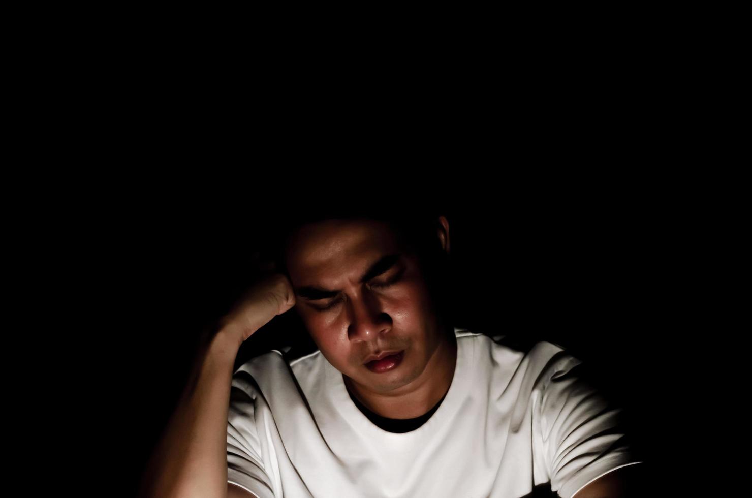 Asian miserable depressed man sitting alone in dark background. Depression and mental health concept. photo