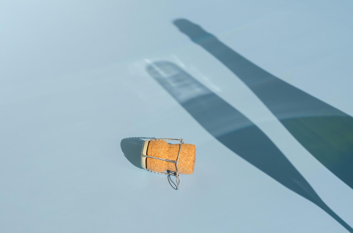 A Champagne or sparking wine cork with shadow of glass and bottle on blue background. Summer concept. photo