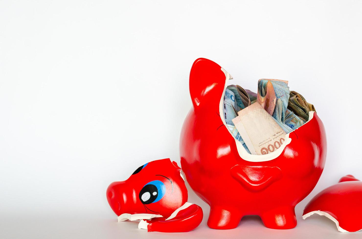 Red piggy bank breaking with Thai baht bank note inside put on white background. photo