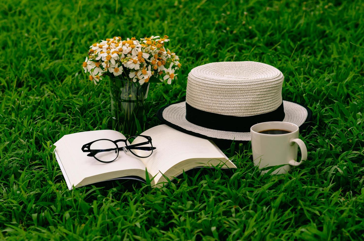 Leisure in morning at garden with coffee, book , hat and flowers on the lawn. photo