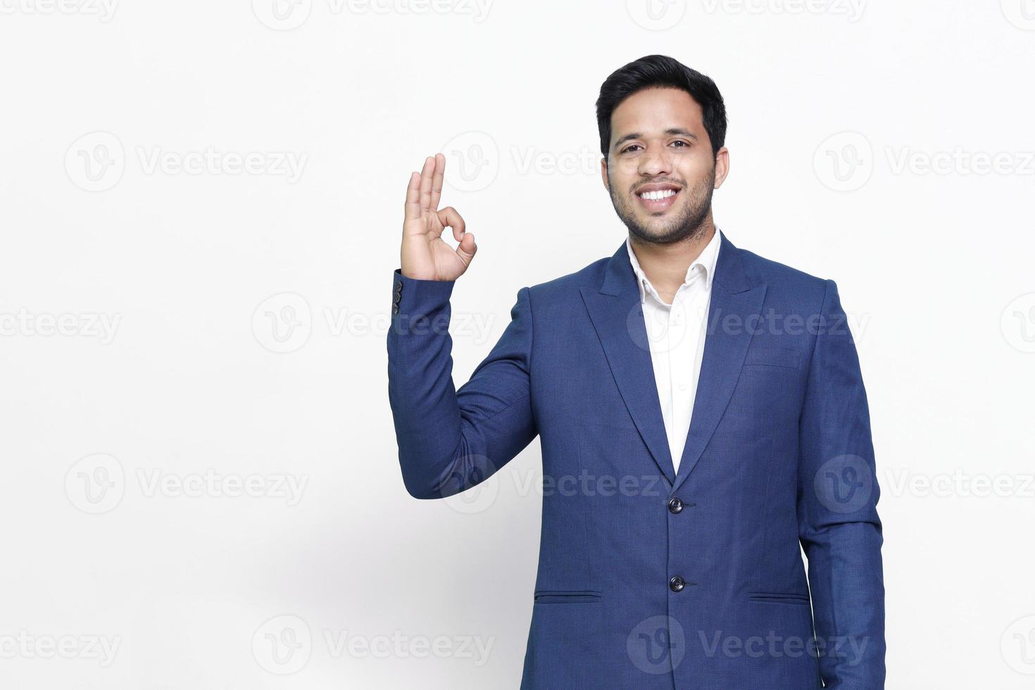 Portrait of a cheerful young man showing okay gesture isolated on the white isolated background. photo
