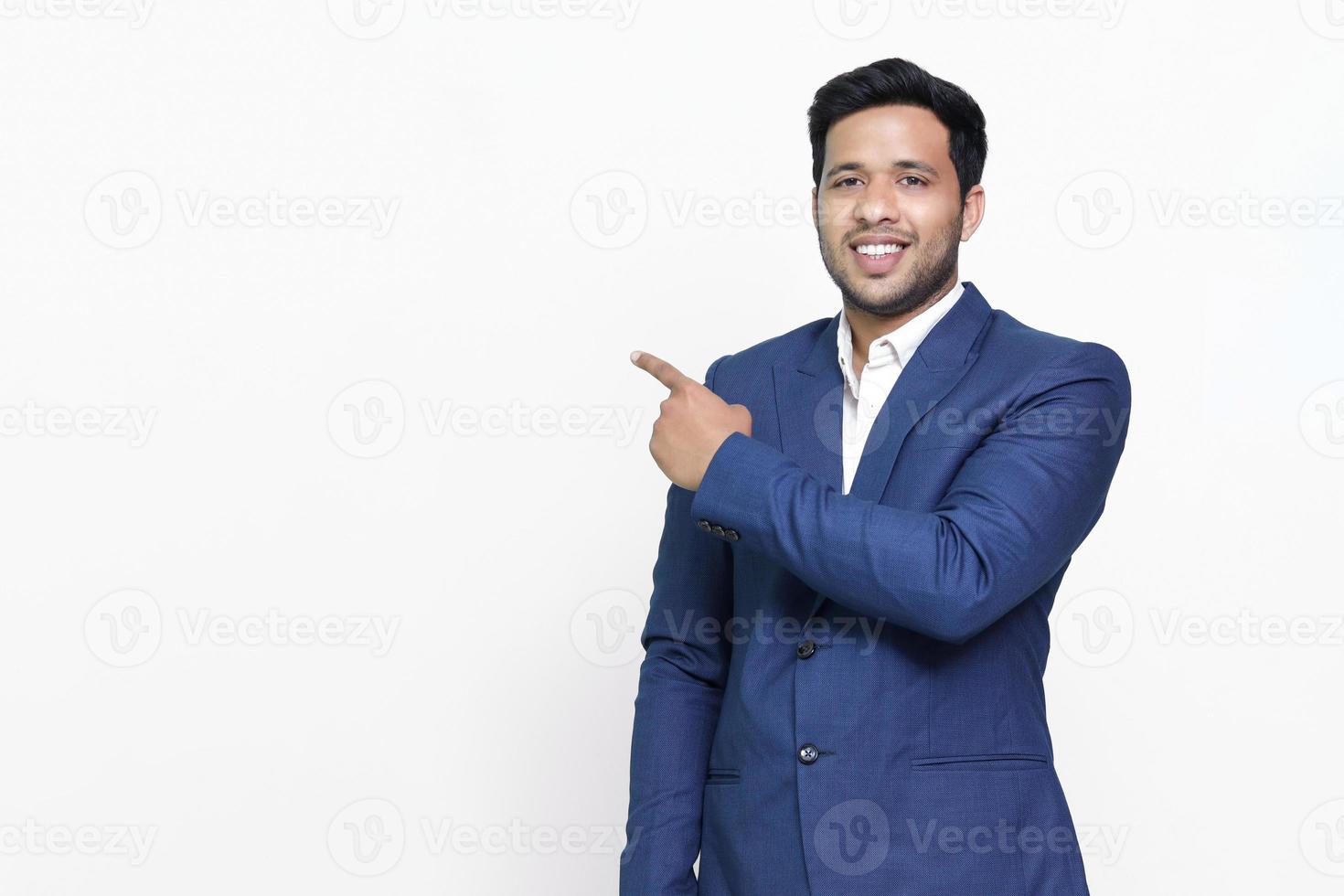 Portrait of a happy businessman pointing finger away over white background. photo