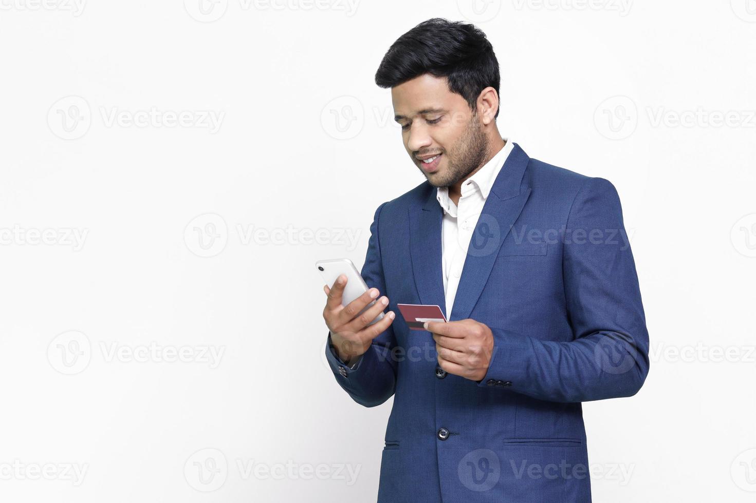 Handsome man makes a payment, using a credit card and smartphone on isolated background. photo