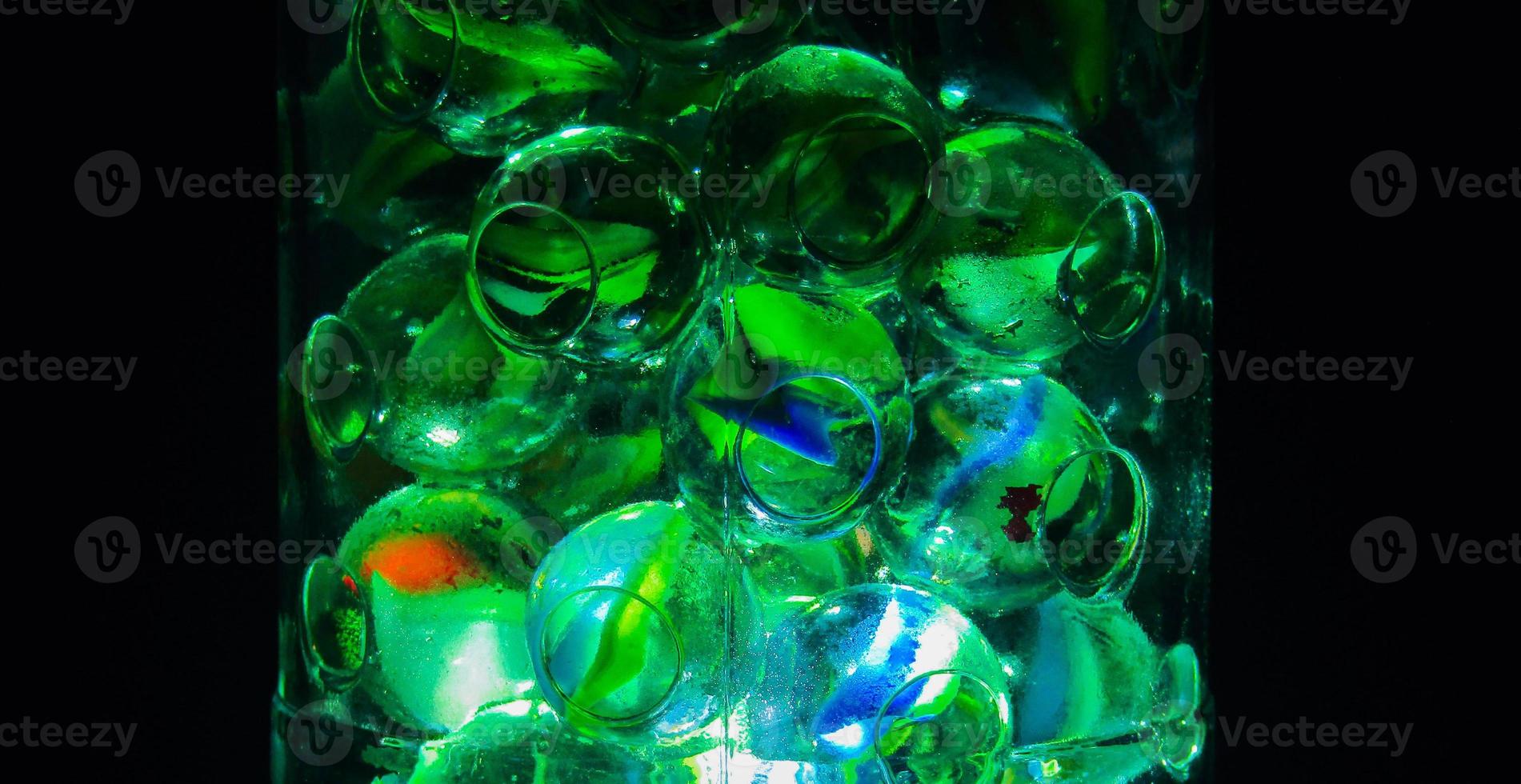 Close-up shot of glass marbles inside a bottle with a dark background. Diversity of marbles color photo