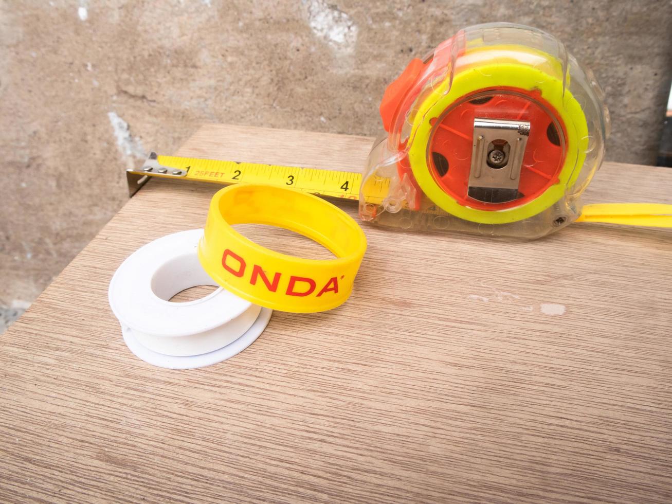 Sidoarjo, Jawa timur, Indonesia, 2022 -  Close-up photo of the 'Onda' brand of pipe tape and measuring tape on a brown wooden background