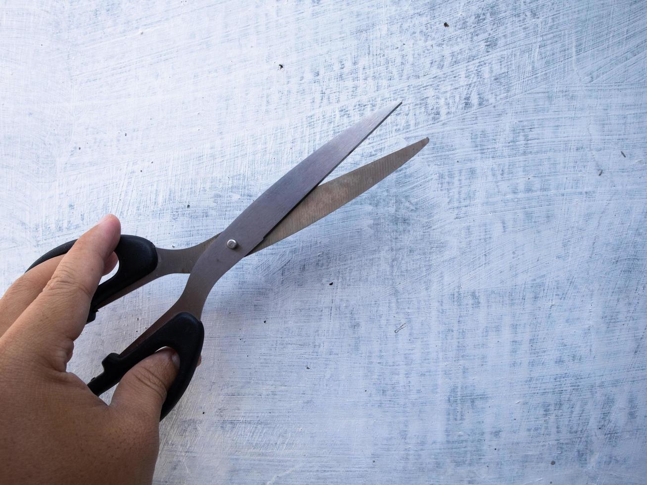 a man holding scissors in his left hand against a white wall background photo