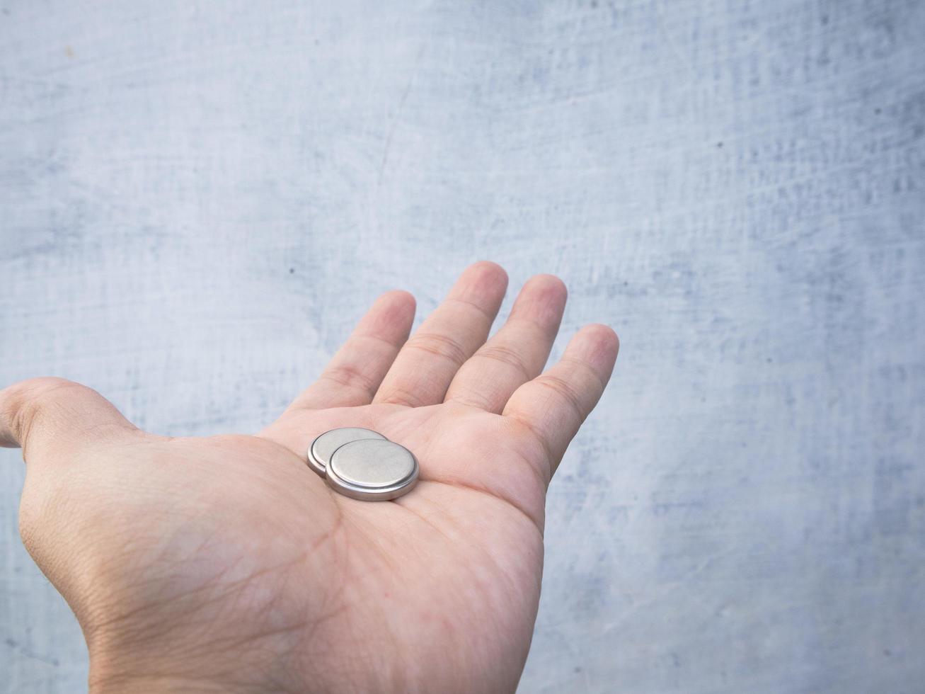 a man puts 2 pieces of cmos battery in his hand photo