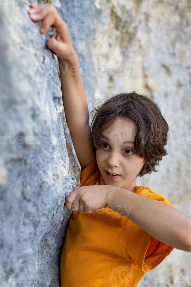 A little rock climber is training to climb a boulder photo