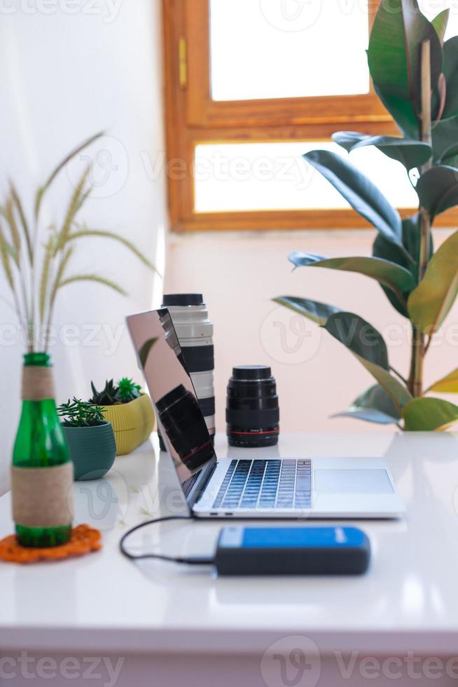 Photographer's workplace, laptop and camera lenses on a white table photo