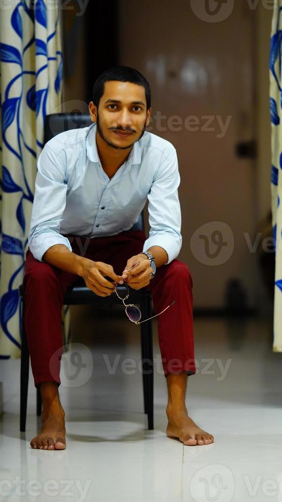 indian young handsome man sitting on chair at home photo