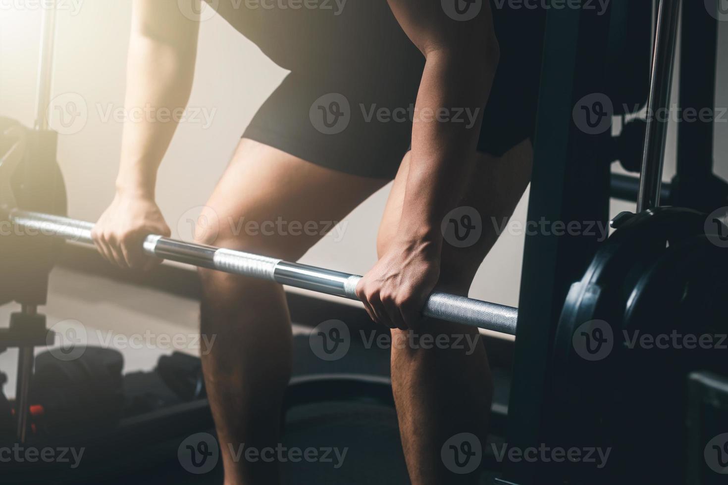 man exercising with barbell, weight training building body strength At the gym in the morning sun. photo