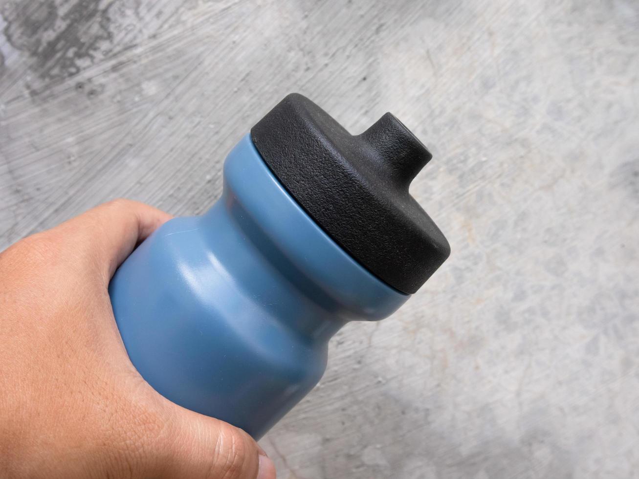 man holding a dark blue sport water bottle in hand photo