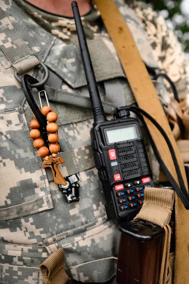 walkie-talkie y rosario con cruz en el pecho de un soldado, guerra y fe en dios. foto