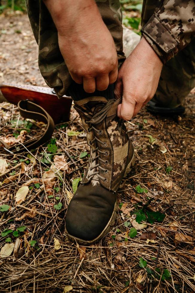 el soldado ata los cordones en sus tobillos. foto