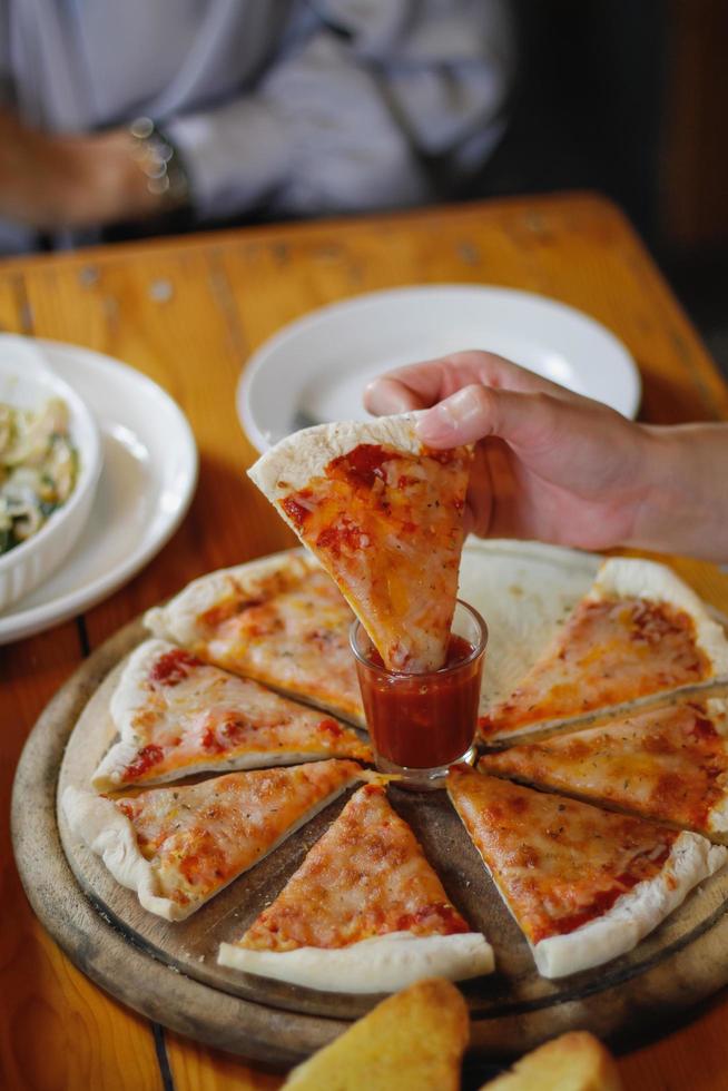 A young woman is happy to see the food on the table and choose the pizza menu to eat with good taste. Pizza menus are perfect for banquets among friends and family as they are comfortable to eat photo