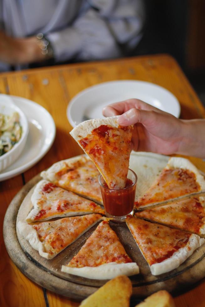 una joven está feliz de ver la comida en la mesa y elegir el menú de pizza para comer con buen gusto. los menús de pizza son perfectos para banquetes entre amigos y familiares ya que son cómodos para comer foto