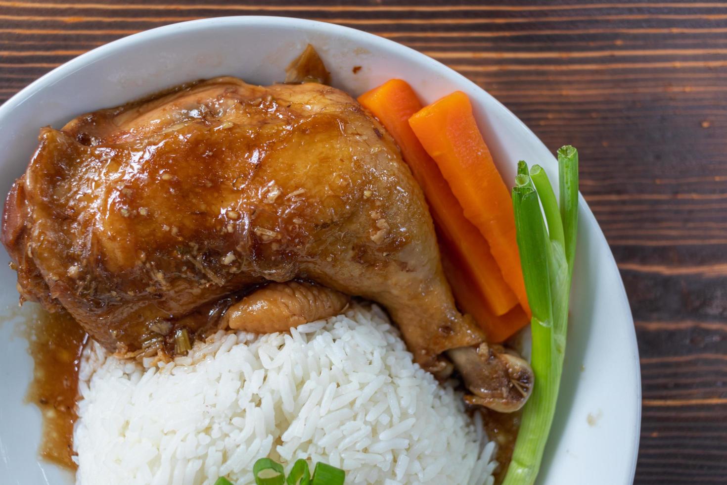 Roasted chicken thighs and drumsticks are served with jasmine rice and fresh vegetables in a white plate. Chicken thighs baked in sweet and delicious sauce are served with hot steamed rice on a plate. photo