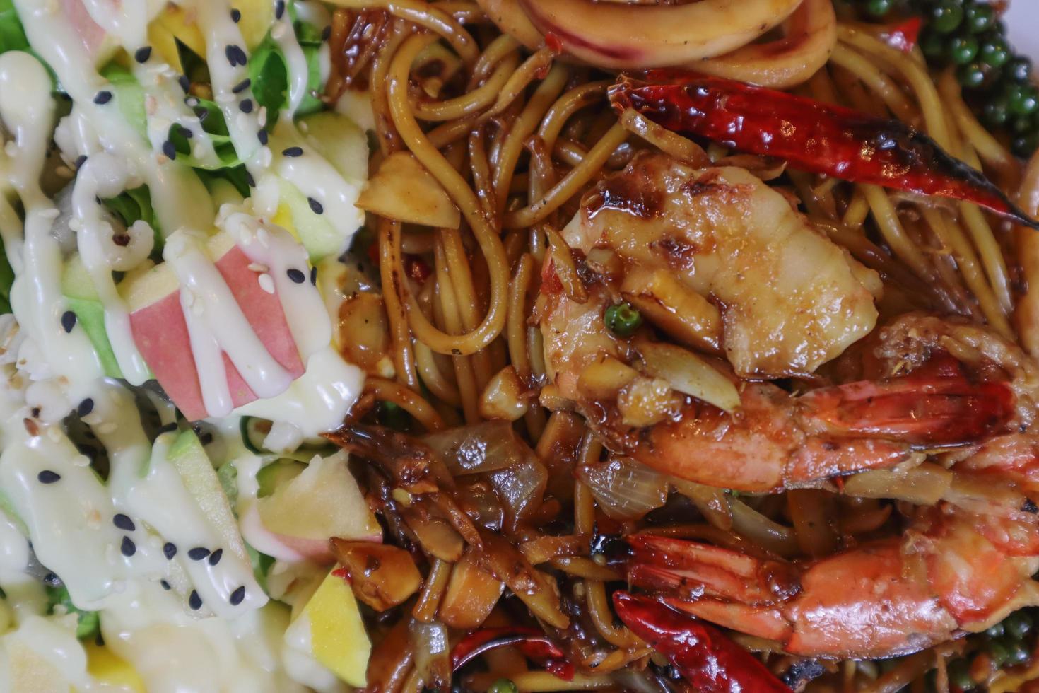 Asian woman eating spaghetti with spicy seafood sauce in a restaurant. The spicy seafood spaghetti was served in a plate and placed on the dining table as the woman ordered. photo